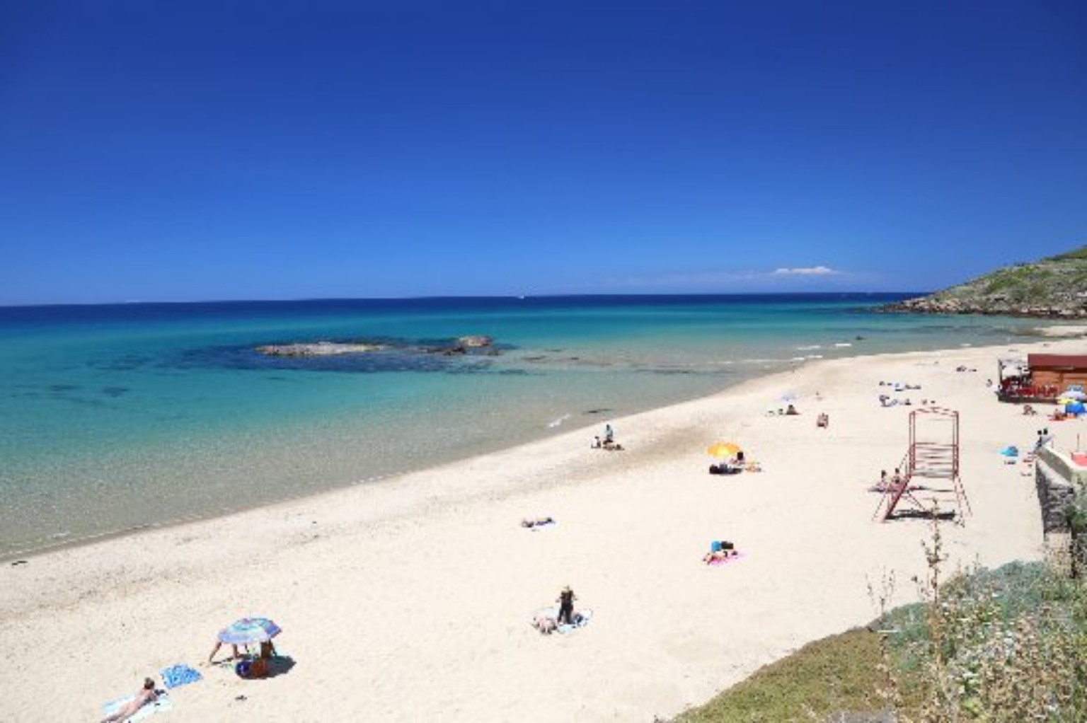 La spiaggia di Ampurias a Lu Bagnu, con sabbia chiara, scogli e mare turchese