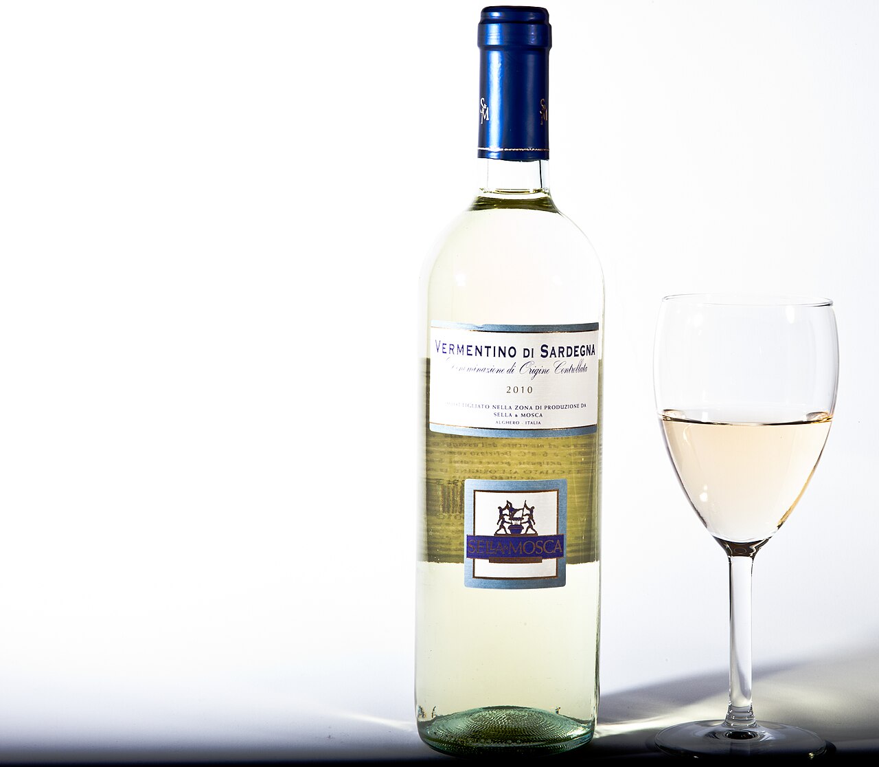 Bottiglia di Vermentino di Sardegna Sella e Mosca e calice di vino bianco